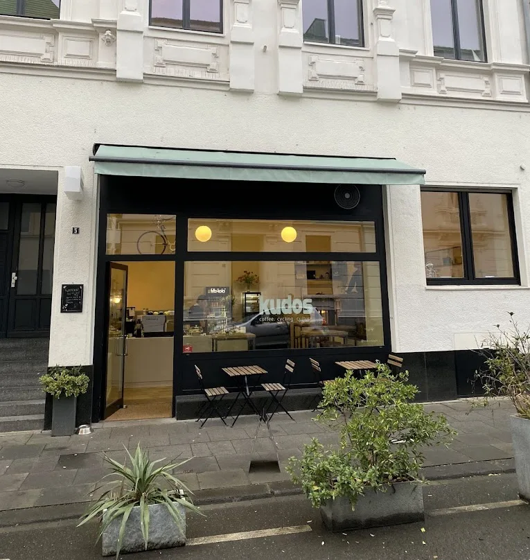 Außenansicht des kudos to you Cafés in der Colmantstraße in Bonn mit Markise, Fensterfront und Bistro-Stühlen